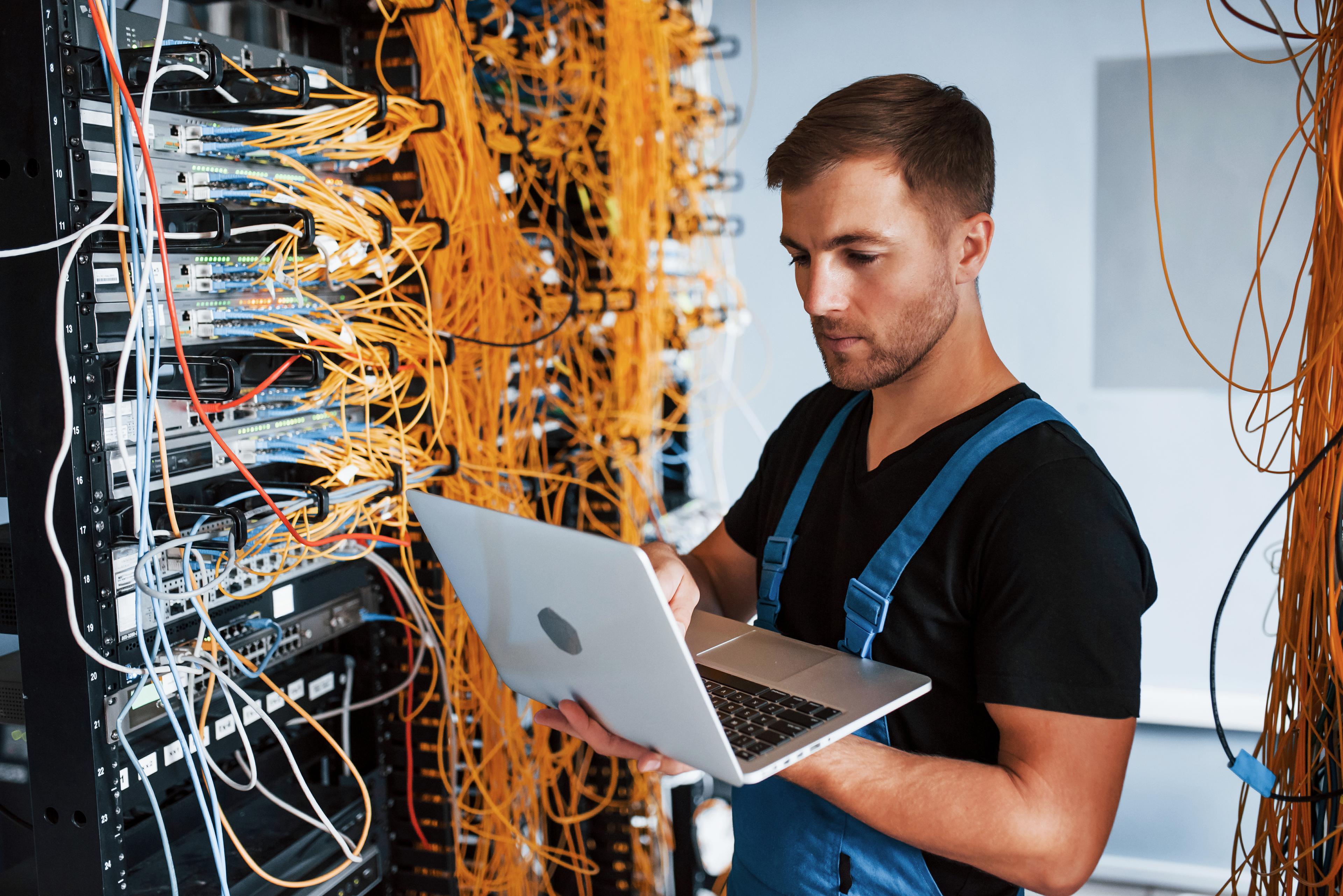 Person working on a server rack with a laptop in hand